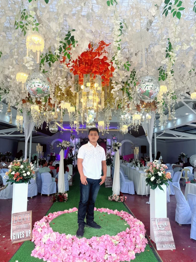 About confident man standing with arms crossed in a beautifully decorated venue, reflecting a proud self and positive outlook.
